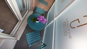 Un pequeño balcón con una mesa redonda, una planta en maceta y una silla.