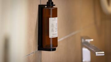 Une bouteille de shampoing marron, dotée d’un distributeur à pompe, est fixée au mur.