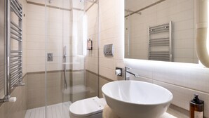 Un baño moderno con ducha envuelta en vidrio, lavamanos blanco y un inodoro.
