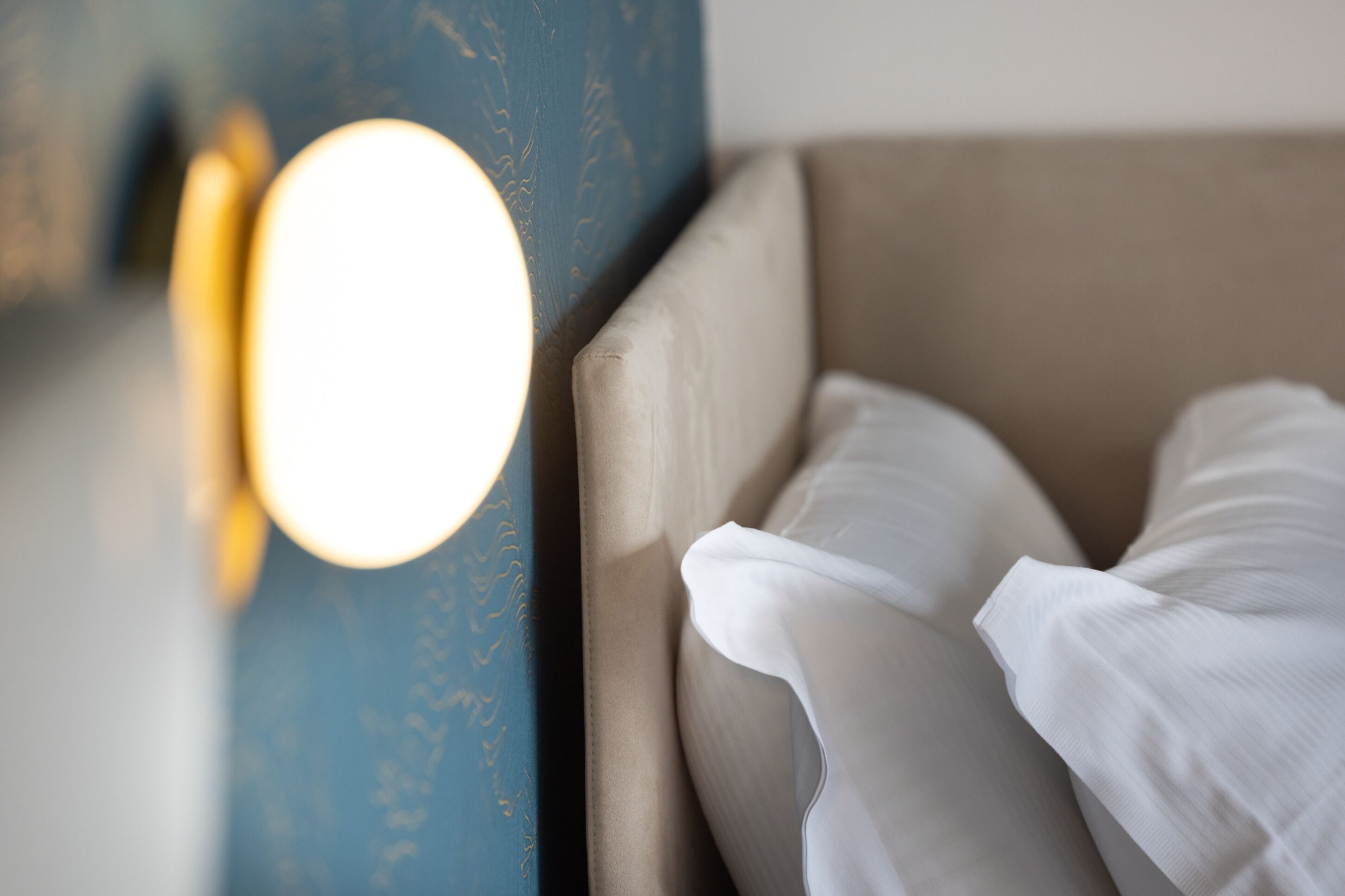A close-up of a bed with white linens and a headboard.