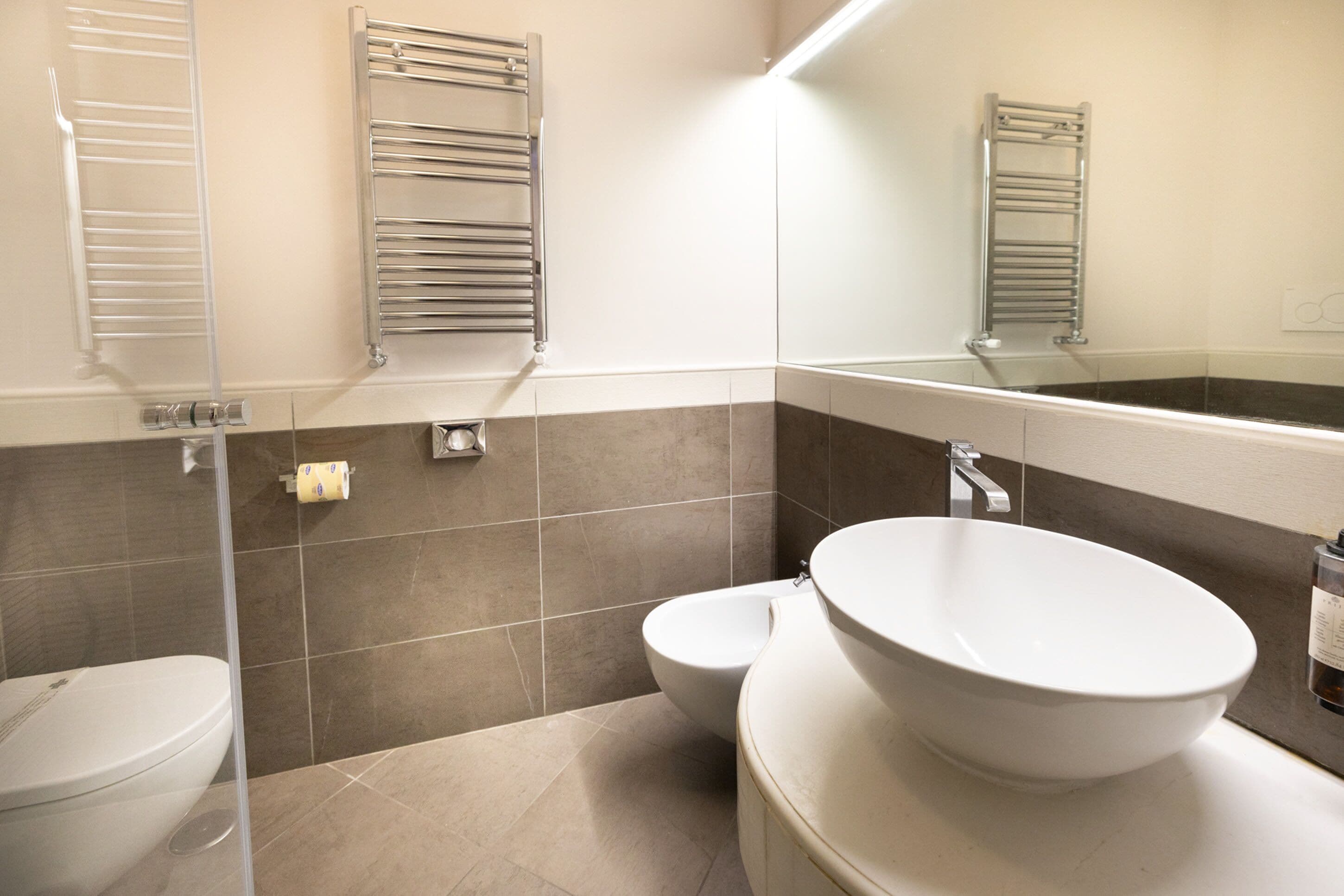 A modern bathroom with a toilet, bidet, and a large vessel sink.