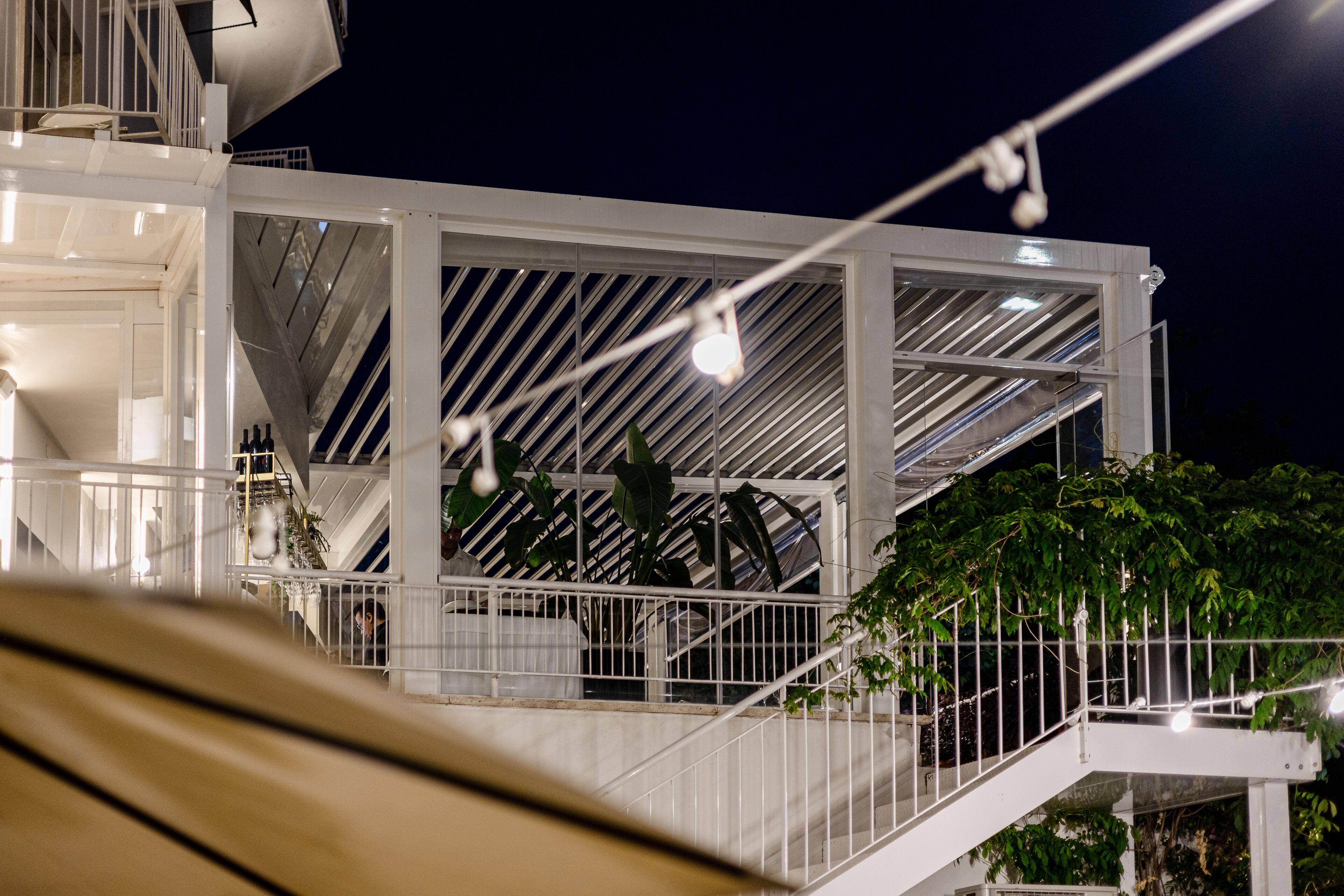 A white, modern building with a glass facade and a metal staircase.