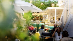 An outdoor seating area with tables and chairs, a bar with shelves of bottles, and a staircase leading to an upper level. - Hotel Villa Zaccardi (Rome)