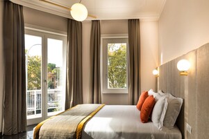 A hotel room with a large bed, curtains, a balcony, and a view of trees.