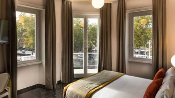 A hotel room with a bed, a chair, and a balcony with a view of the street.