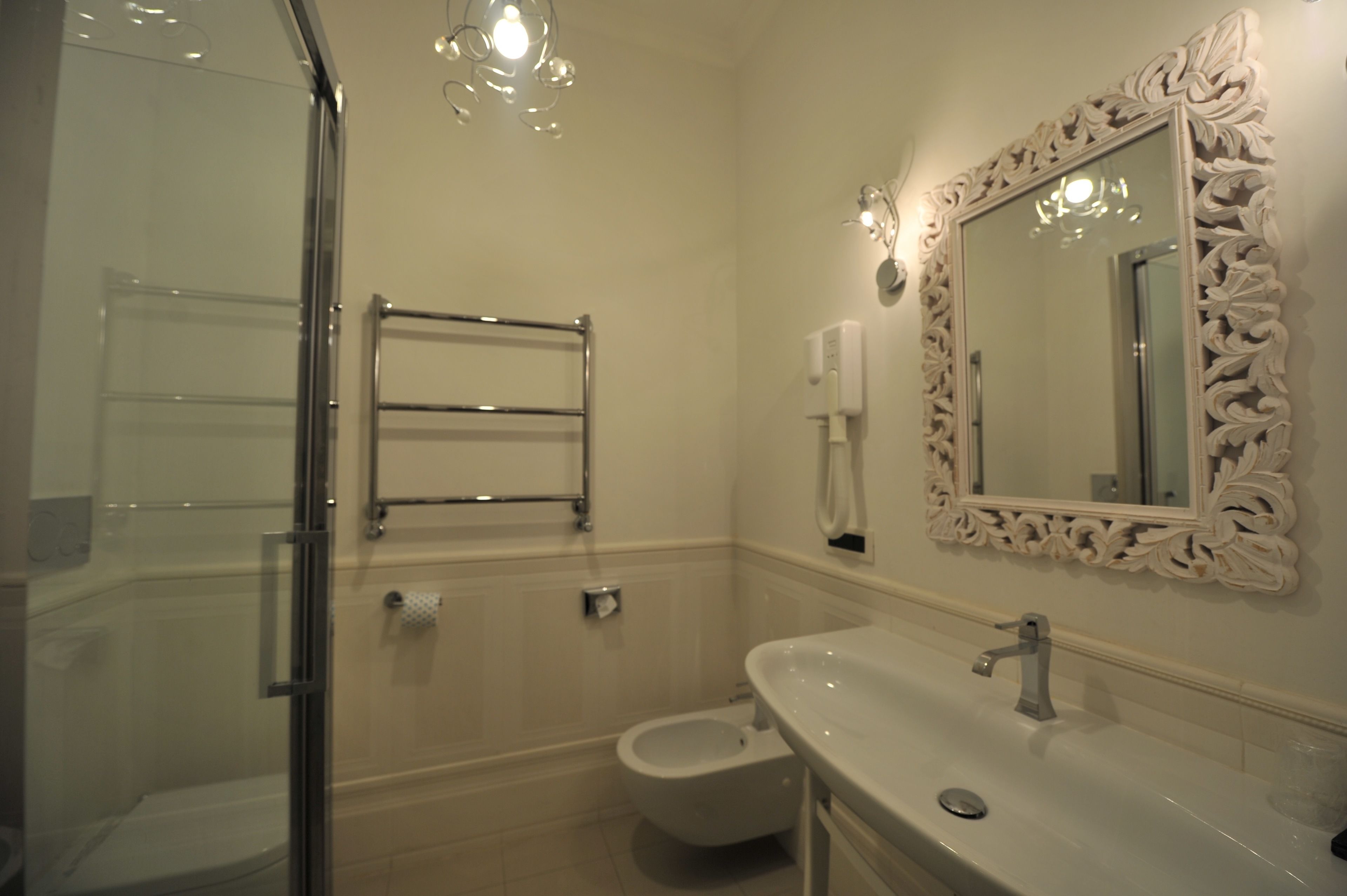 A bathroom with a glass shower enclosure, a toilet, a sink with a mirror, and a towel rack.