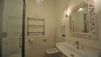 A bathroom with a glass shower enclosure, a toilet, a sink with a mirror, and a towel rack.