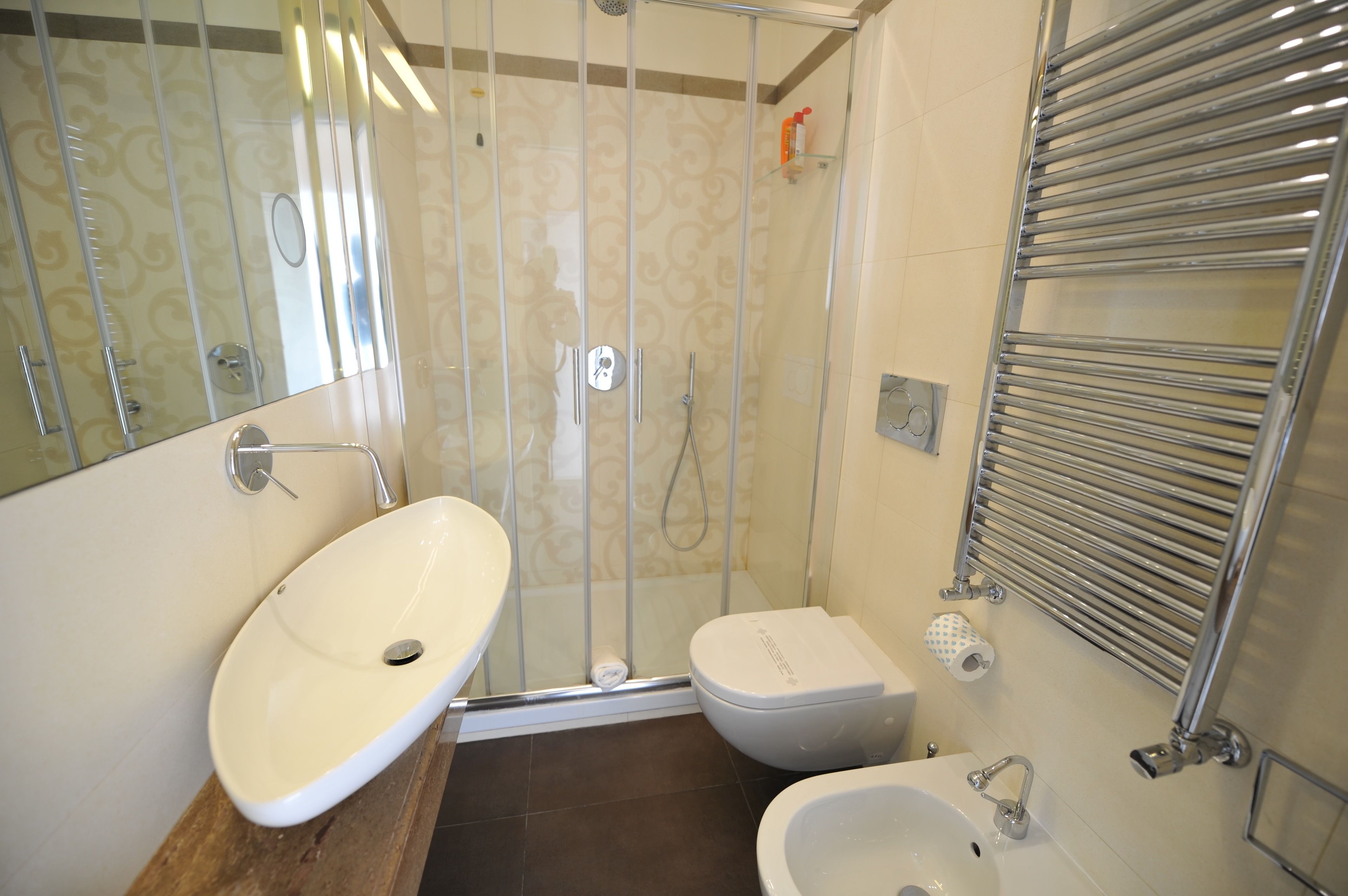 A bathroom with a glass-enclosed shower, a toilet, and two sinks.