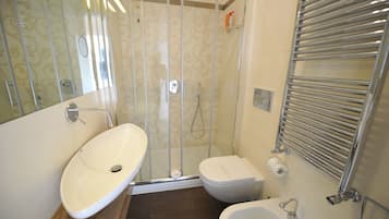 A bathroom with a glass-enclosed shower, a toilet, and two sinks.
