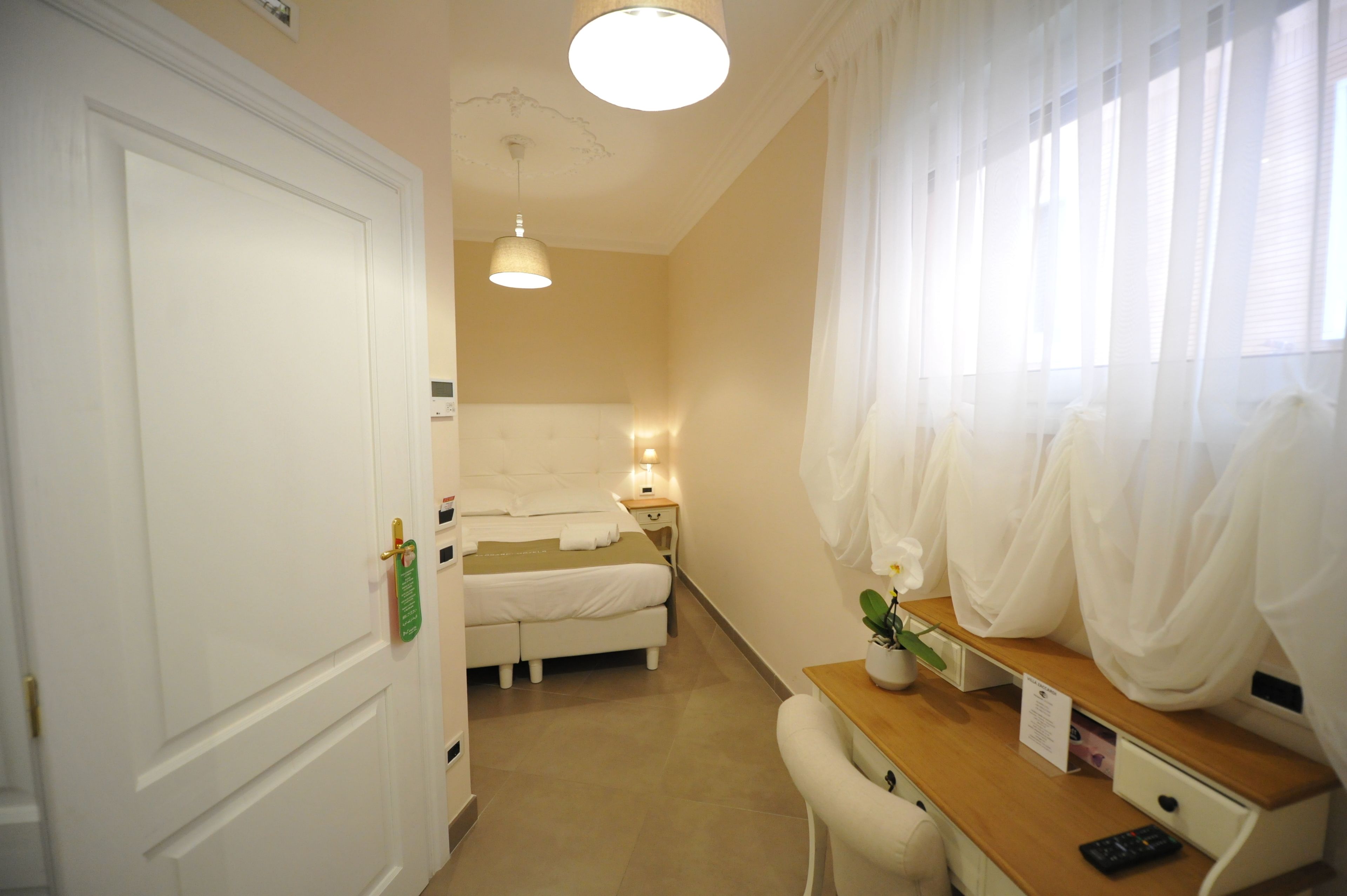 Une chambre d’hôtel avec un lit, une table de chevet, une lampe et des rideaux.