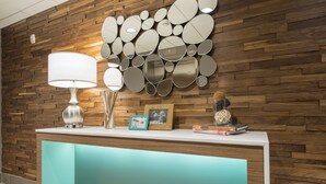 Una recepción con un muro de madera, una lámpara blanca y una pared de espejos.