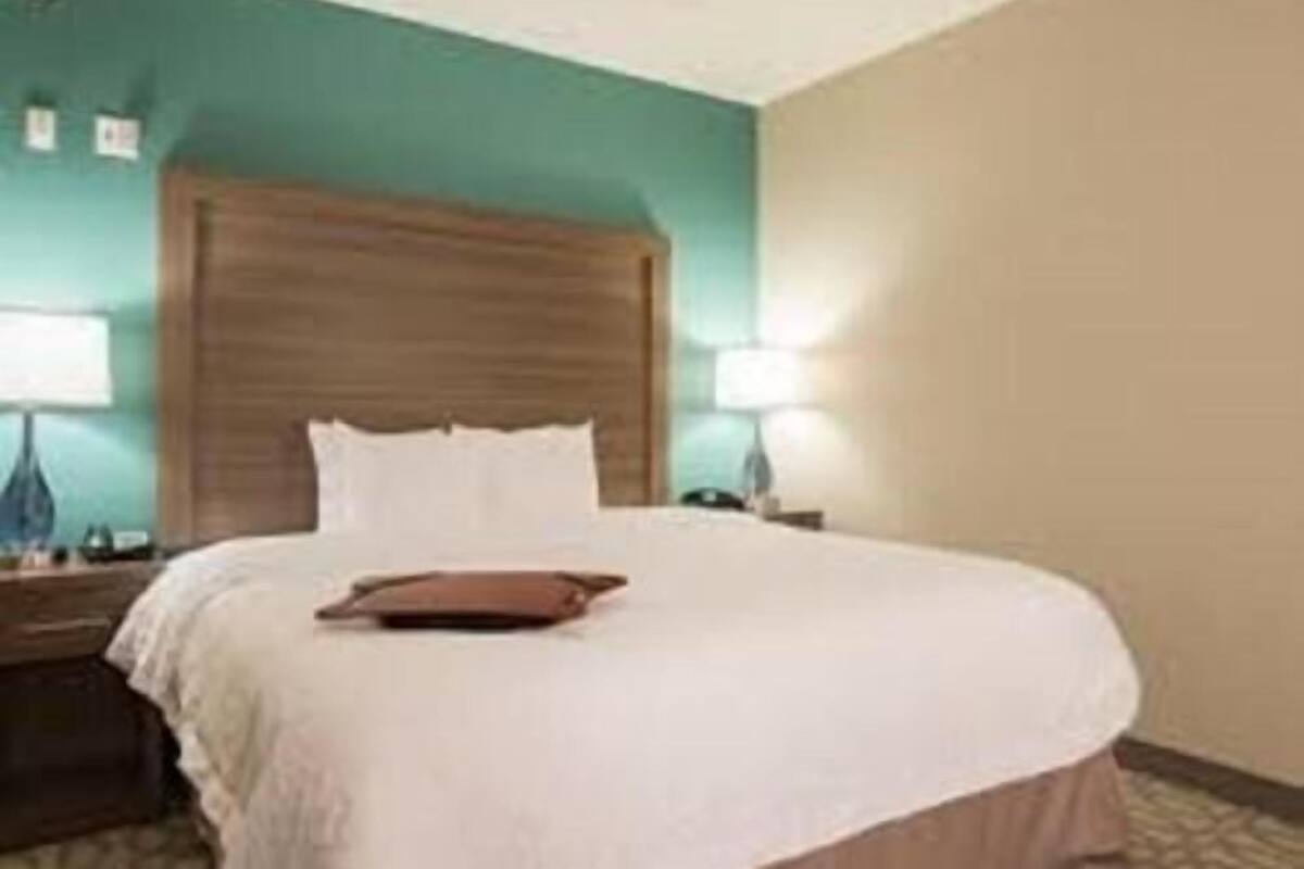 Una habitación de hotel con cama, lámparas de noche y mesita de noche.