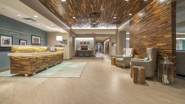 Un área de recepción con un mostrador de madera, una sala de espera con sillas y una pared decorada con cuadros enmarcados.