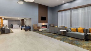 A modern living room with a fireplace, sofas, and a TV. - La Quinta Inn & Suites by Wyndham Knoxville Papermill (Knoxville)