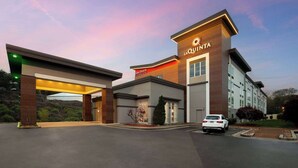 A hotel entrance with a modern design, a car parked in the driveway, and a clear sky in the background. - La Quinta Inn & Suites by Wyndham Knoxville Papermill (Knoxville)