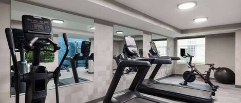 Un gimnasio con cintas de correr, elíptica y bicicleta estática.