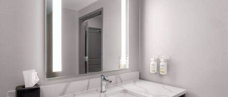 A bathroom with a large mirror, a double sink, and a towel rack.