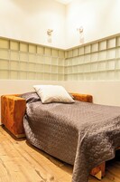 Un dormitorio con cama, mesitas de noche de madera, cabecera con diseño de rejilla e iluminación empotrada en la pared.