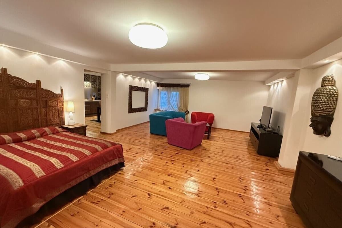 A spacious room with a large bed, a sofa, and a TV.