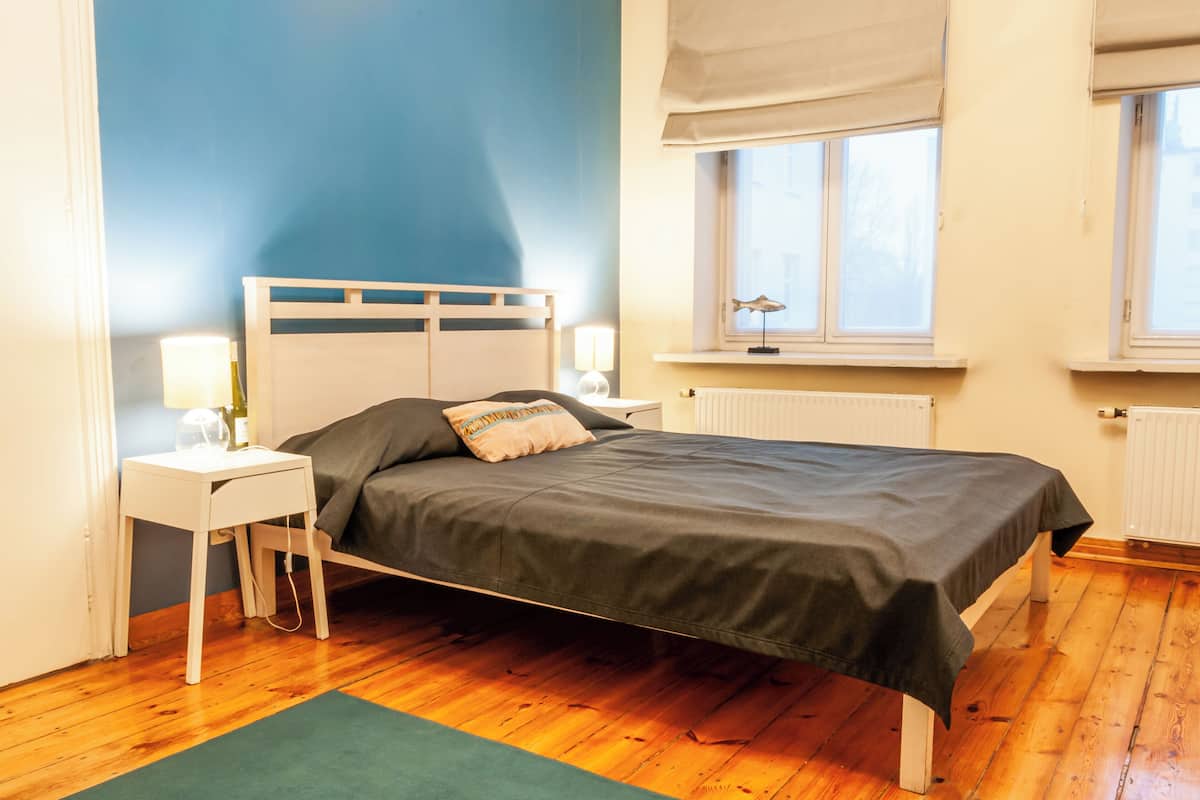 A bedroom with a bed, nightstands, a window, and a radiator.