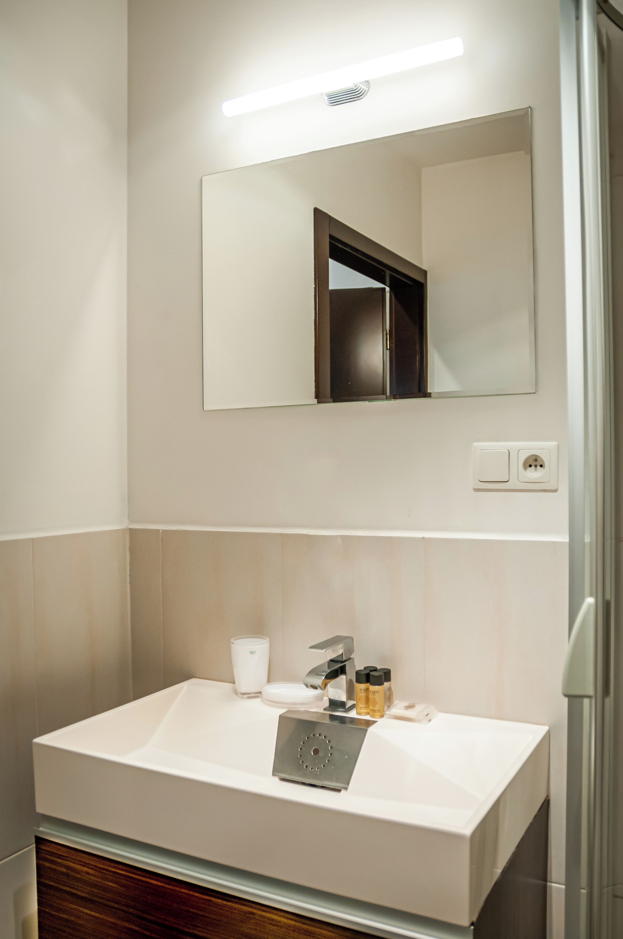 Une salle de bain moderne avec un grand lavabo blanc, un miroir et un espace douche.