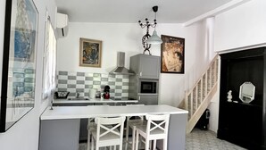Una cocina moderna con una isla central, taburetes blancos y un piso con diseño.