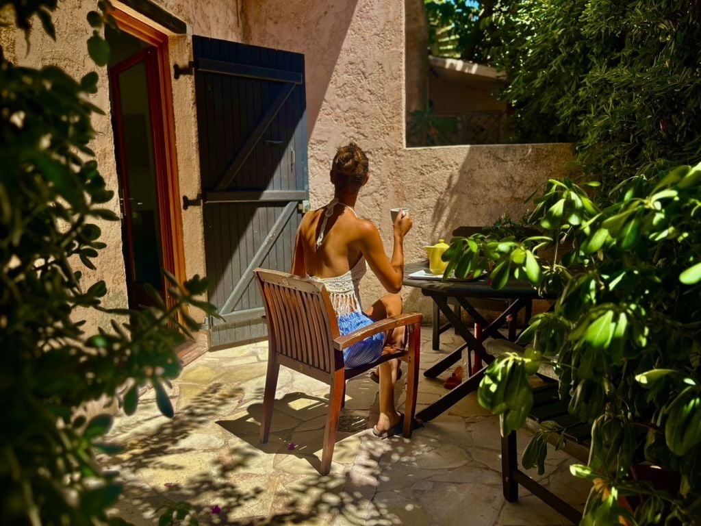 Une personne assise à une table en plein air, sur une chaise, entourée de plantes en pot.