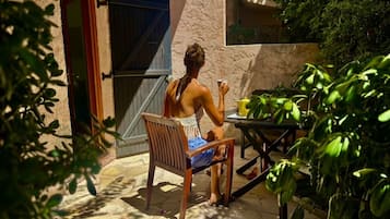 Une personne assise à une table en plein air, sur une chaise, entourée de plantes en pot.