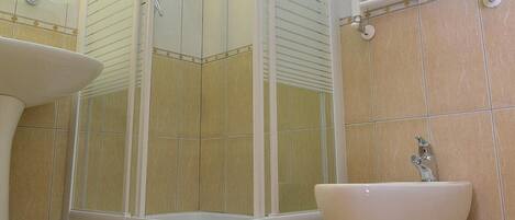 A modern bathroom with a glass-enclosed shower, a pedestal sink, and a toilet.
