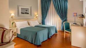 A hotel room with two beds, a desk, a chair, a lamp, a picture on the wall, and a window with curtains. - Ottaviano Guest House (Rome)