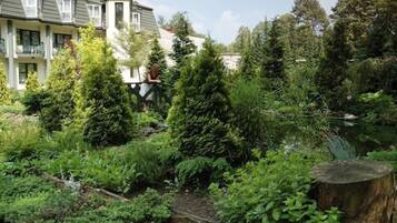 Un barrio residencial con una casa, abundante vegetación y un estanque.