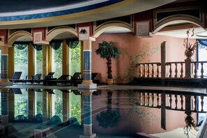 A pool with clear water, lounge chairs, and potted plants.