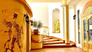 Una imponente escalera con una planta en maceta, una estatua y un muro con un relieve.