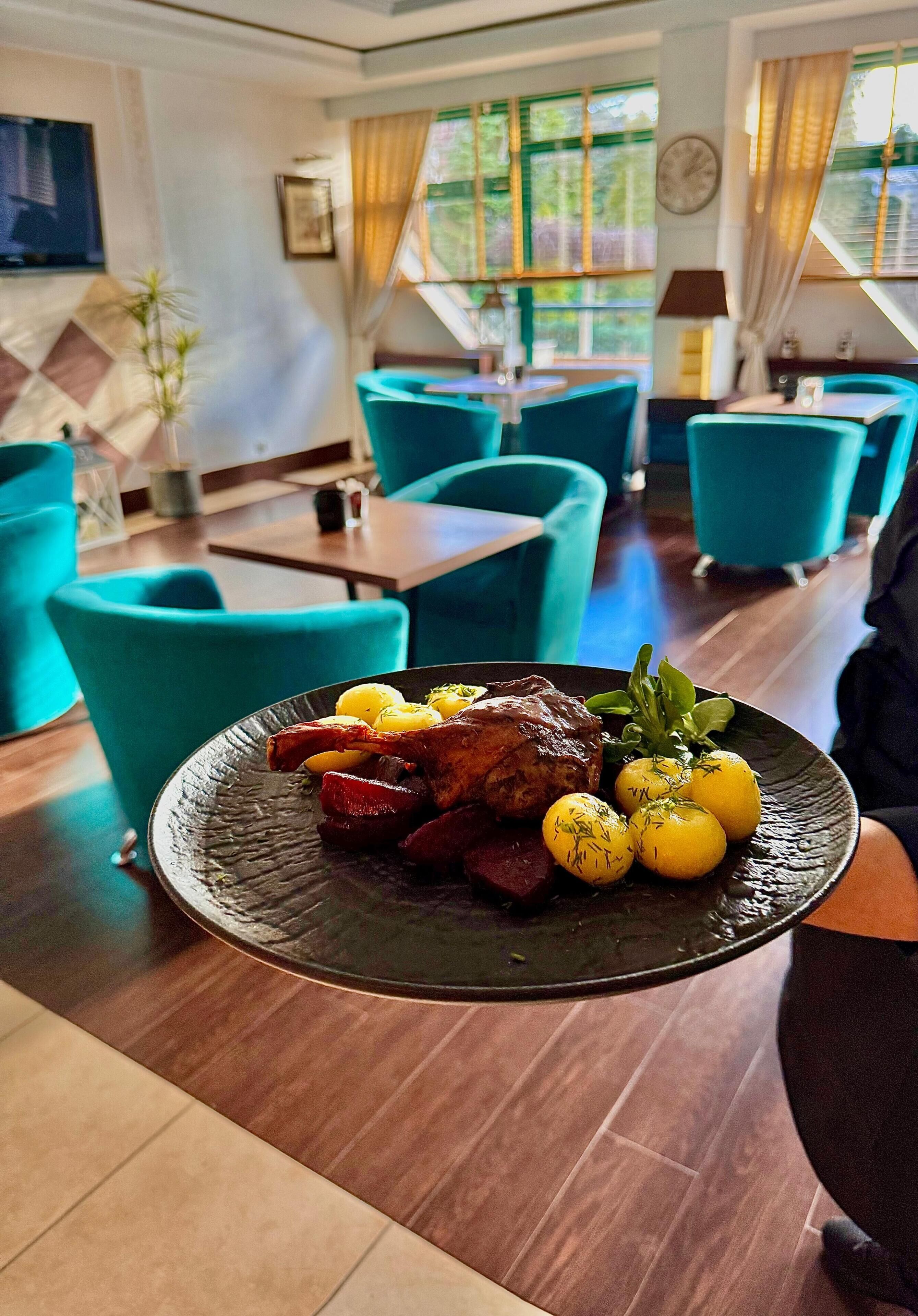 A dining area with teal chairs, a wooden table, and a plate of food.