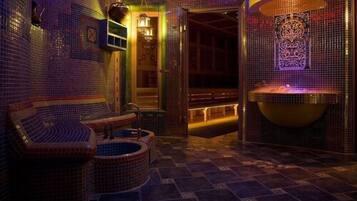 A spa room with a bathtub, a seating area, and a decorative wall.
