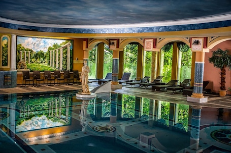 A pool area with a statue, lounge chairs, and a mural of ancient columns.. Papuga Park Hotel Wellness Marrakesz & SPA