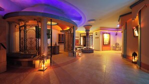 Vestíbulo de hotel con techo curvo, columnas y mostrador de recepción.