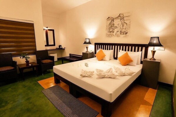 Una habitación de hotel con una cama grande, dos mesitas de noche con lámparas, una silla, un escritorio y una obra de arte colgada en la pared.