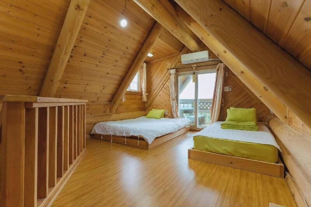Une cabane en bois avec deux lits, un balcon et un appareil de climatisation.