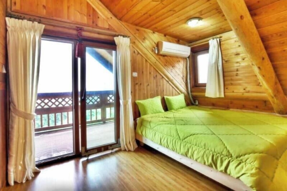 Une chambre dans une cabane en bois, avec un lit, des rideaux et une fenêtre.