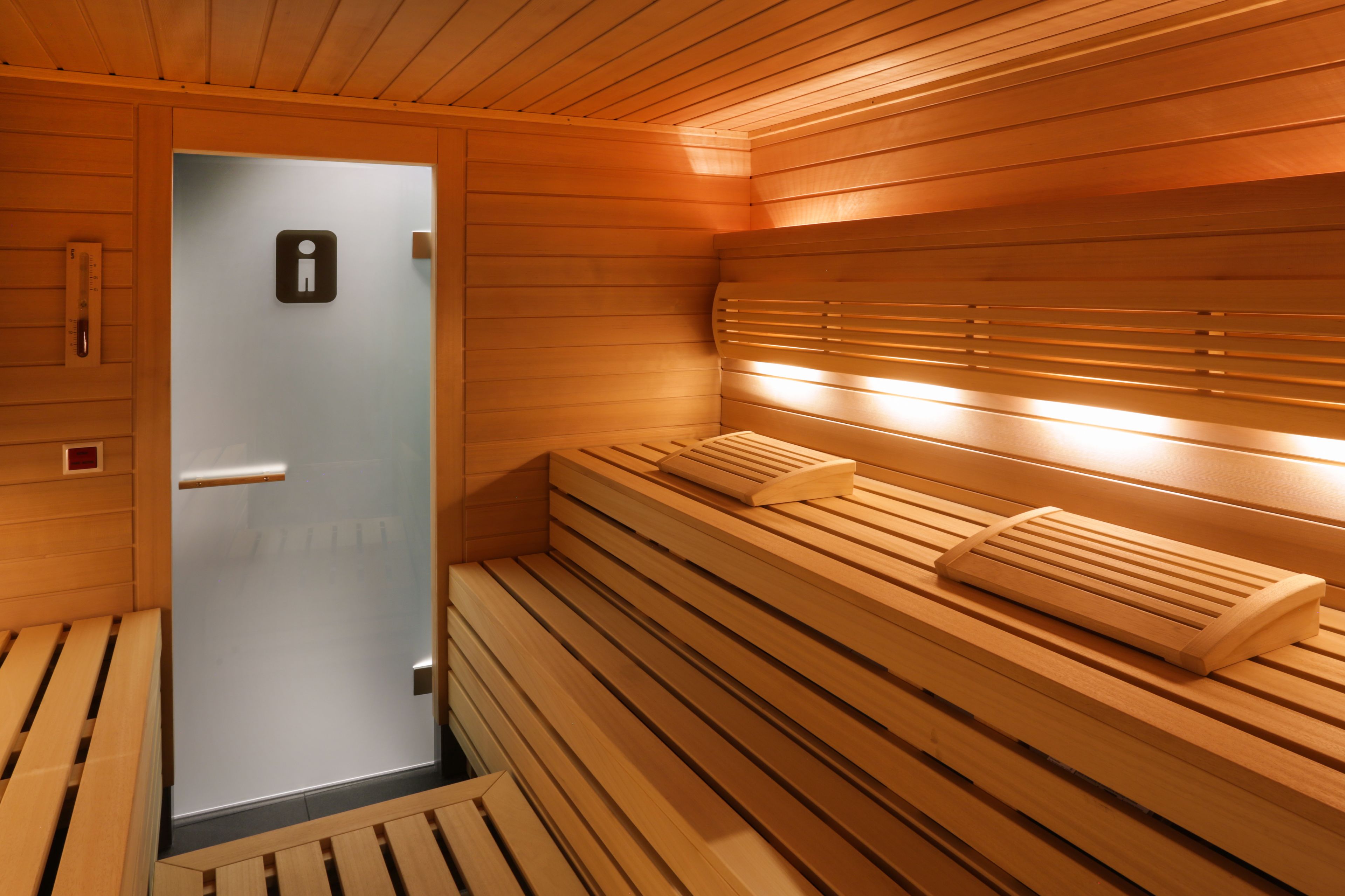 A sauna room with wooden benches and a glass door.