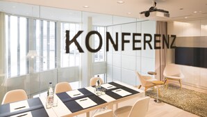 A modern conference room with glass walls, a large projection screen, and a table set for meetings.
