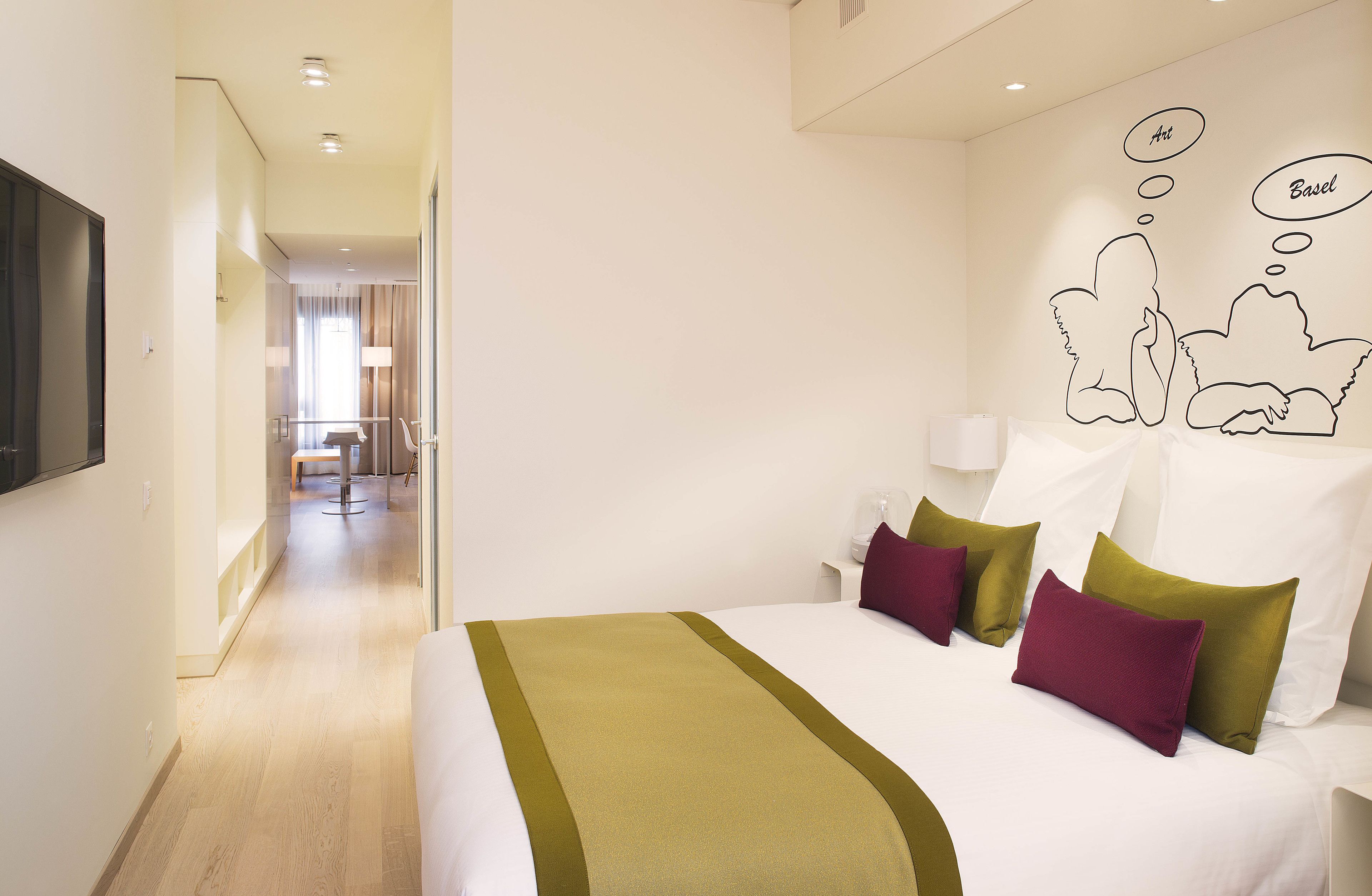 Ein Hotelzimmer mit Bett, Kissen, einem Nachttisch und einer Wand mit einer Comic-Wolke.