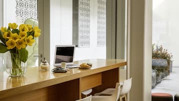 Et moderne køkken med en træbordplade, en bærbar computer, en vase med gule blomster og en kaffekop.