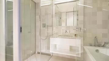 Une salle de bain moderne dotée d’une douche à parois de verre, d’un meuble-lavabo blanc avec un plan de travail en granit et d’une baignoire îlot.