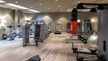 A gym with various exercise equipment, including treadmills, weight machines, and a punching bag.