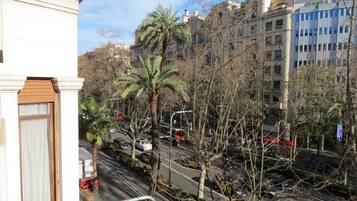 A street view with buildings, palm trees, and parked cars.
