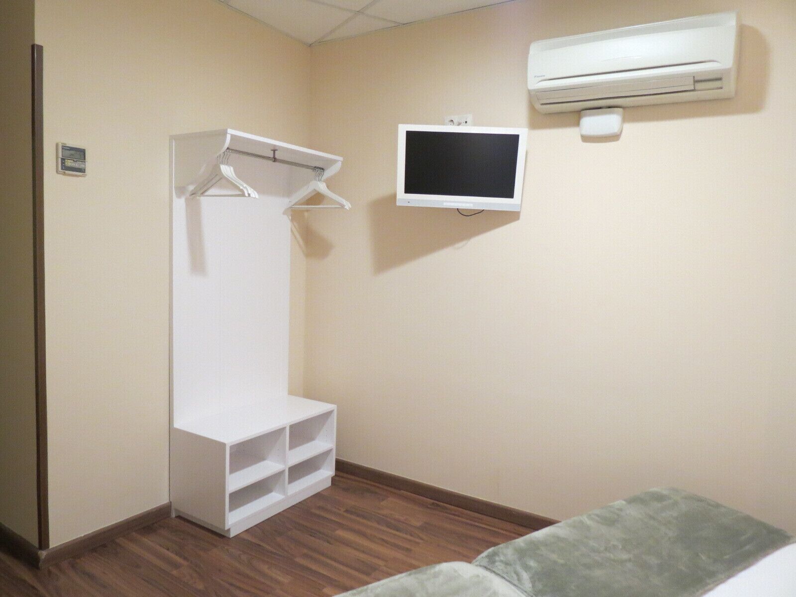 A room with a white wardrobe, a flat-screen TV, and an air conditioner.