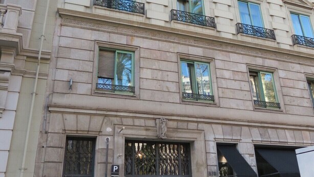 Un immeuble à étages, de style architectural classique, caractérisé par une façade symétrique avec des fenêtres régulièrement espacées et des éléments décoratifs.