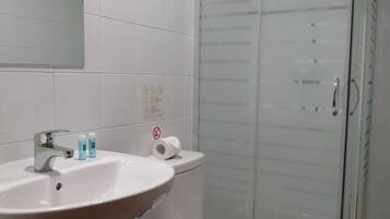 Un baño con ducha de vidrio, lavamanos blanco y un inodoro.